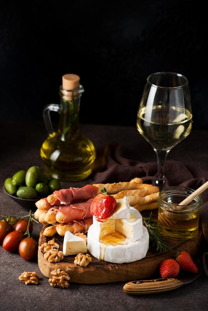 Brie cheese, camembert, grissini, jamon, wine, nuts, honey. Snacks for wine. Italian snacks