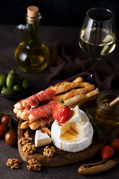 Brie cheese, camembert, grissini, jamon, wine, nuts, honey. Snacks for wine. Italian snacks