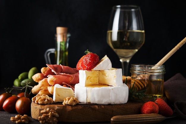 Brie cheese, camembert, grissini, jamon, wine, nuts, honey. Snacks for wine. Italian snacks