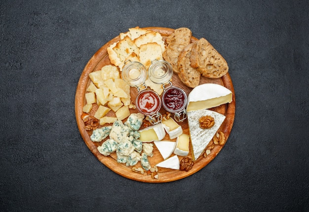 Brie cheese on a wooden Board with bread and sweet jam