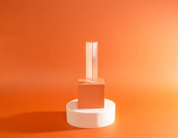 Bright balance of three figures (round, cube and prism) on a orange surface