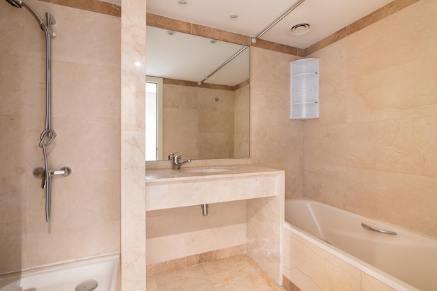 Bright bathroom with tiled walls and floors in warm light beige tones washbasin with large mirror