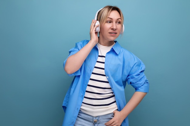 Bright blond girl dressed in a casual shirt listens to music in the application in wireless