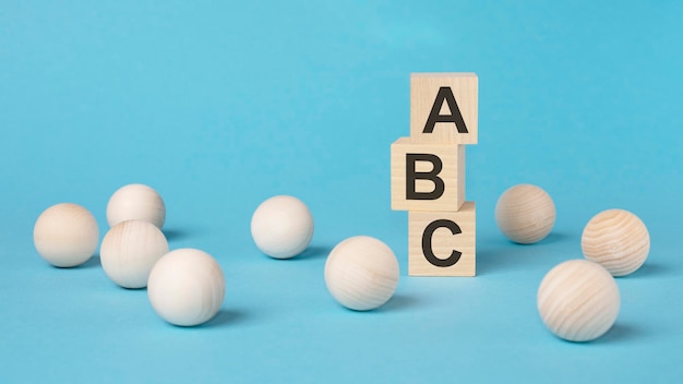 On a bright blue background light wooden blocks and cubes with the text ABC cubes is reflected from the surface ABC short for Always Be Closing