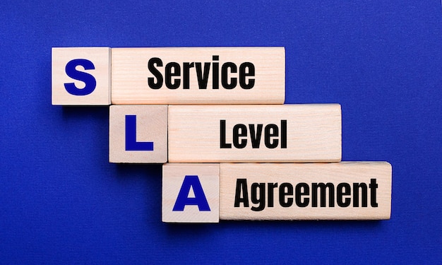 On a bright blue background light wooden blocks and cubes with the text SLA Service Level Agreement