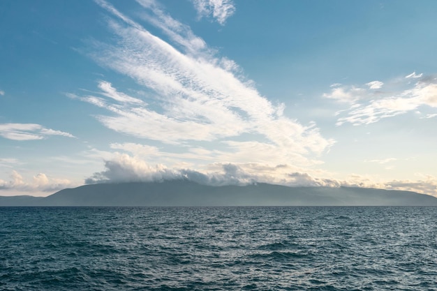 Bright blue ocean in a cloudy blue sky with islands on the horizon in albania