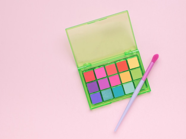 A bright brush and colorful eye shadow on a yellow background Flat lay