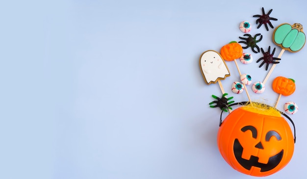 Bright candy bowl pumpkin and treats for halloween on a blue background