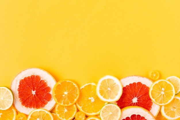 Bright citrus fruits on a yellow background, summer flat lay concept.