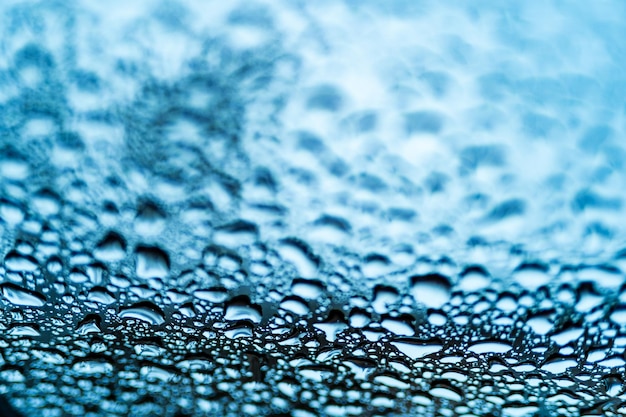 Bright clear bubbles of water drops on the window after the rain on blue background Drops of rain on the glass Macro shot