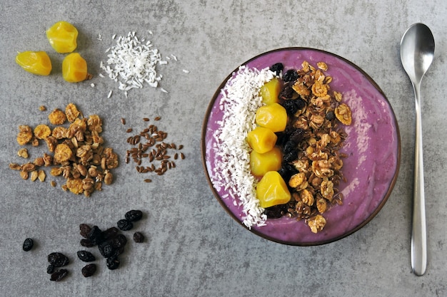 Bright colorful acai bowl with granola and dried fruit.