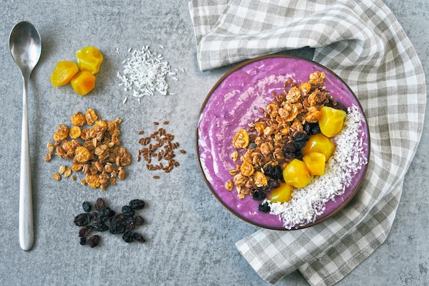 Bright colorful acai bowl with granola and dried fruit.