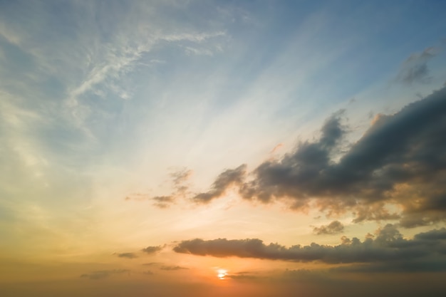 Bright colorful sunset sky with setting sun and vibrant clouds.