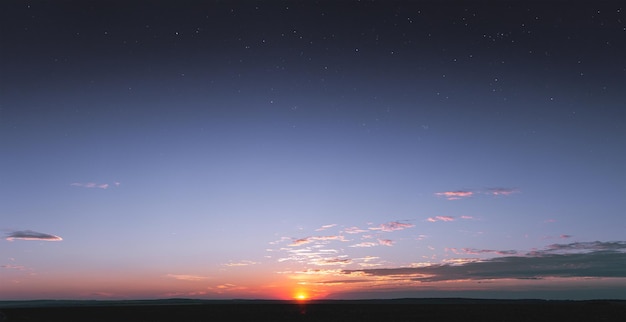 A bright colorful sunset with small saturated clouds against the background of the starry sky. Stars shine through the atmosphere at sunset