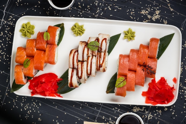 Photo bright and colorful sushi set with different fish and seafood ingredients on stone serving board on dark background