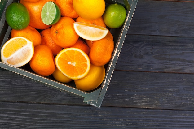 Bright composition of citrus fruits on black wooden background