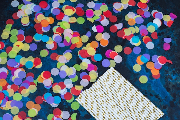 bright confetti and cocktail tubes on a dark blue background