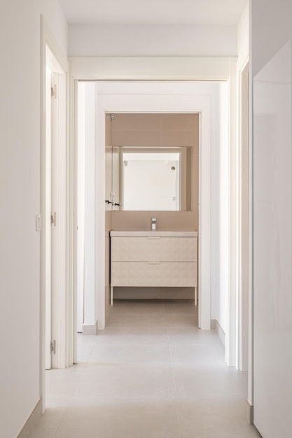 Bright corridor with white walls and tiled floor with a doorway to the bathroom