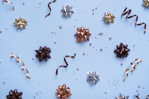 Bright festive background with bows and beads top view New Year Christmas blue background flat lay