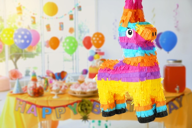 Bright festive pinata hanging indoors at birthday party space for text