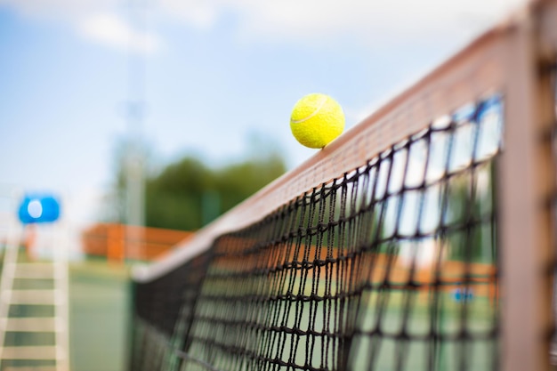 Bright greenish yellow tennis ball hitting the net