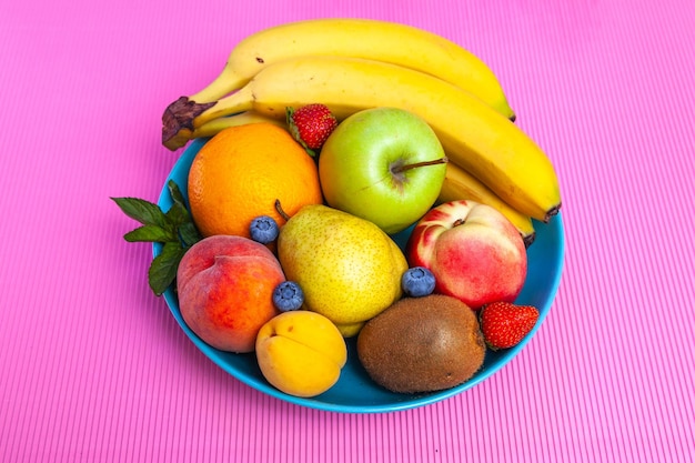 Bright juicy fruits laid out in a plate - blueberries, bananas, pears, apples, mint