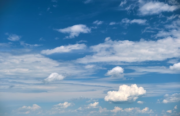 Bright landscape of white puffy cumulus clouds on blue clear sky.