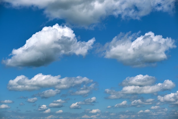 Bright landscape of white puffy cumulus clouds on blue clear sky.