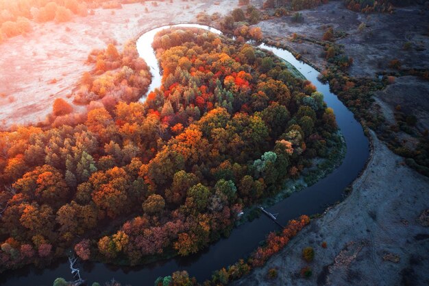 Bright landscape. Winding river, floodplain, dry grass and autumn forest at dawn. Environmentally friendly area.