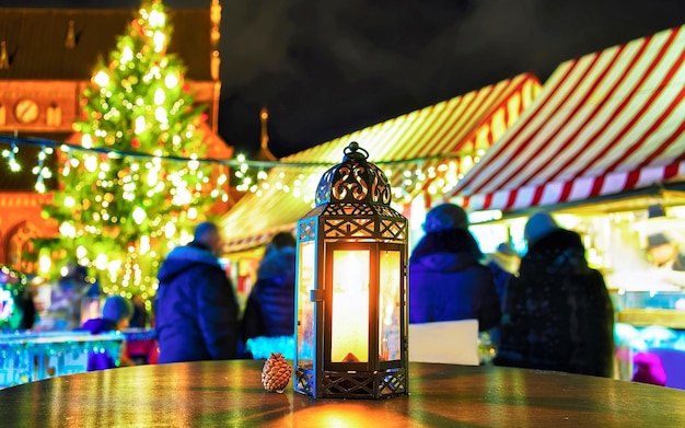 Bright lantern with the candle at table of Christmas Market in Riga, Latvia. Europe in winter. German street Xmas and holiday fair. Advent Decoration and Stalls with Crafts Items on Bazaar