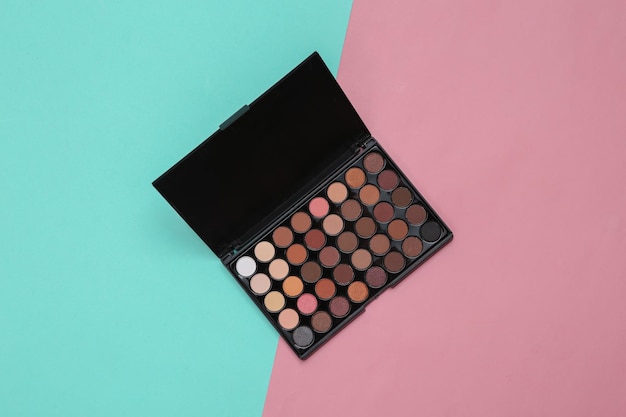 Bright make up eye shadow pallete on pink blue background Beauty still life Top view