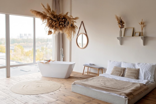 Bright modern boho chic bedroom with a freestanding white bathtub against a panoramic window and dry grass and flowers hanging decor Soft selective focus