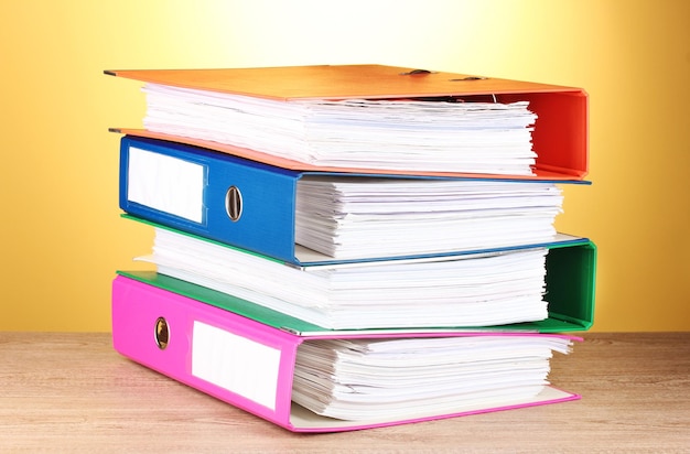 Bright office folders on wooden table on yellow background