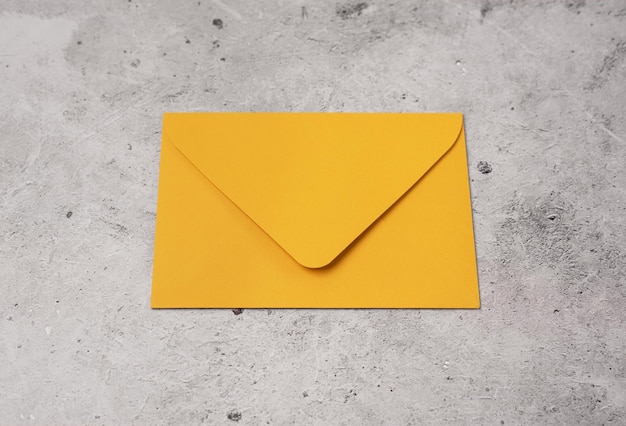 Bright orange envelope close up on a light concrete background