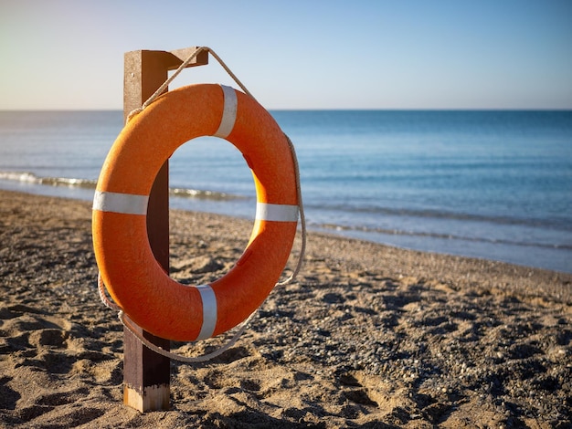 Bright orange lifebuoy on a sandy beach on a Sunny summer day