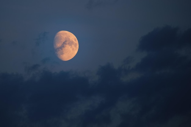 Photo bright orange moon against dark sky and clouds