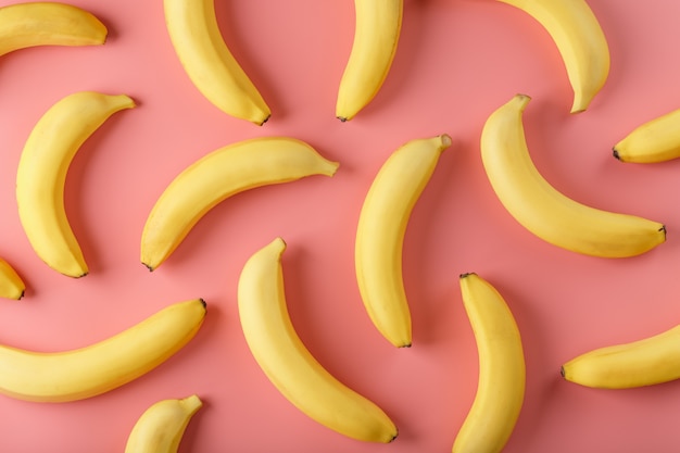 Bright pattern of yellow bananas on a pink background. View from above. Flat lay. Fruit patterns