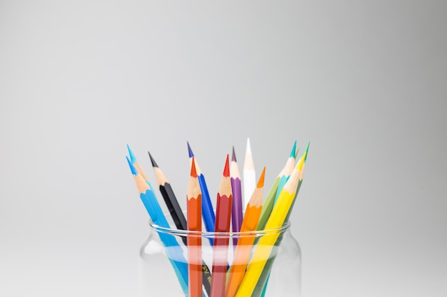 Bright pencils in a glass jar isolated on white background.