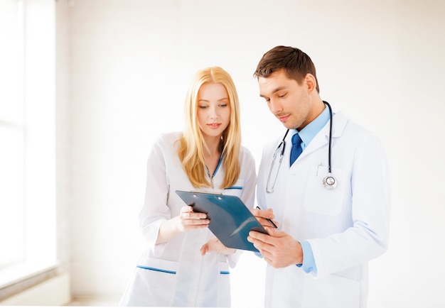 bright picture of two young attractive doctors pointing at blank paper