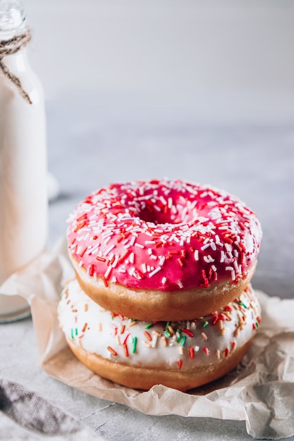 Bright pink donuts and a bottle of milk