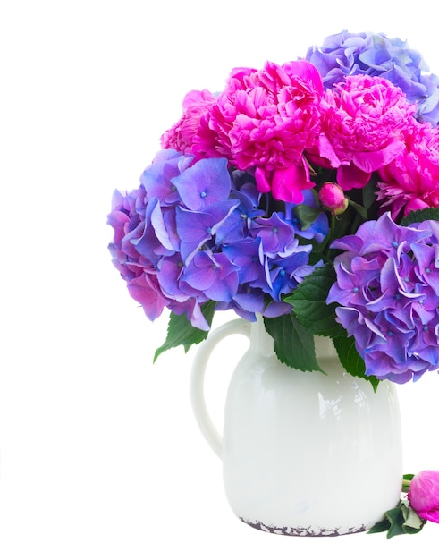 Bright pink peony, eustoma and blue hortensia fresh flowers bouquet in vase close up isolated on white