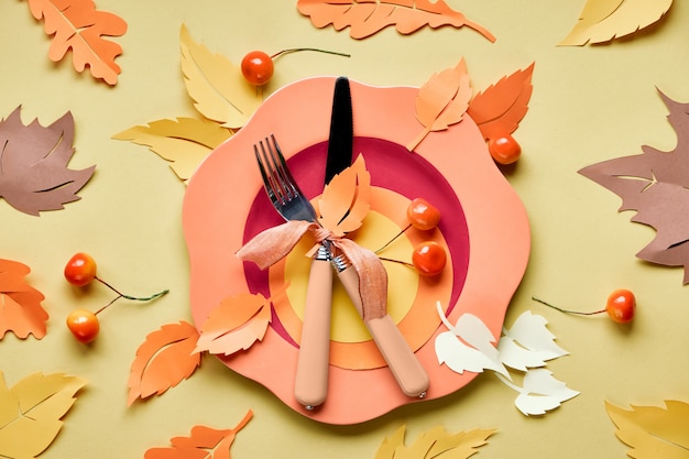 Bright plastic plate on yellow paper with paper Autumn leaves