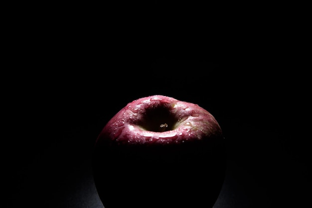 Bright red apple shadow On a black background with water droplets lights are falling with space for text