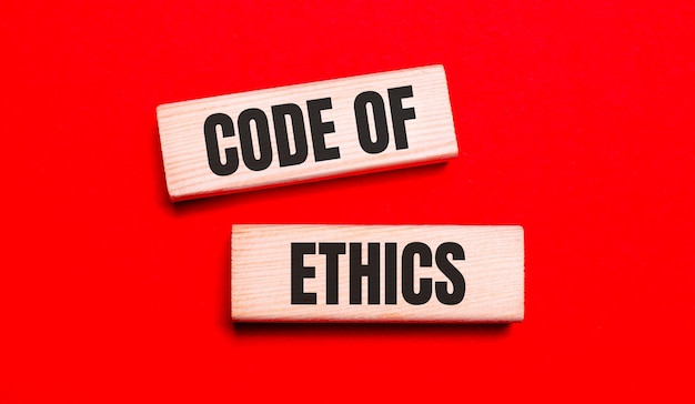 On a bright red background, there are two light wooden blocks with the text CODE OF ETHICS