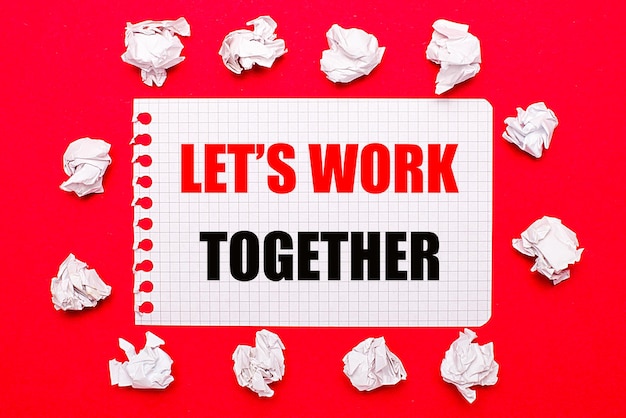 On a bright red background white crumpled sheets of paper and a sheet of paper with the text LET IS WORK TOGETHER