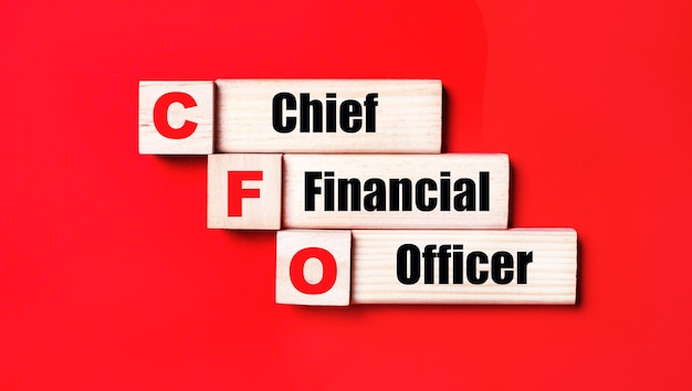 On a bright red background wooden cubes and blocks with the text CFO Chief Financial Officer Manufacturing of wooden toys