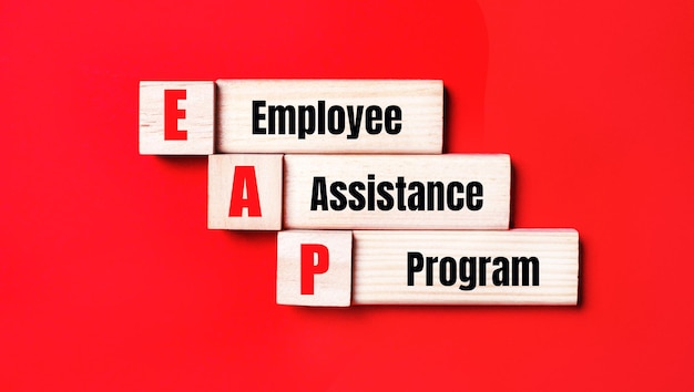 On a bright red background wooden cubes and blocks with the text EAP Employee Assistance Program Manufacturing of wooden toys