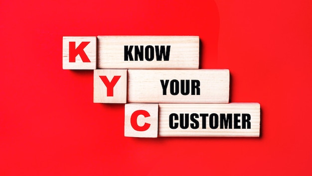 On a bright red background wooden cubes and blocks with the text KYC KNOW YOUR CUSTOMER Manufacturing of wooden toys