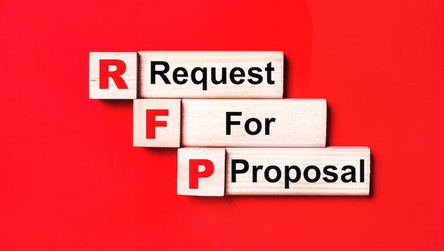 On a bright red background wooden cubes and blocks with the text RFP Request For Proposal Manufacturing of wooden toys