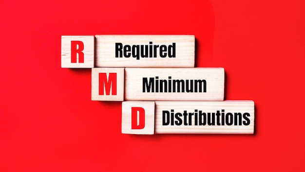 On a bright red background wooden cubes and blocks with the text RMD Required Minimum Distributions Manufacturing of wooden toys